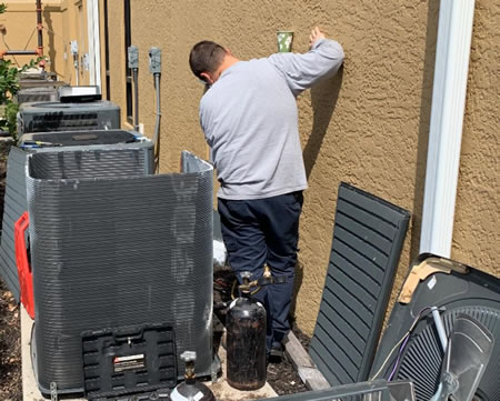 Technician inspecting outdoor AC unit in Fort Myers before hurricane season